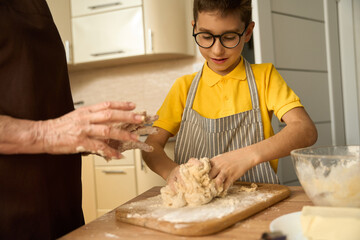 Child preparing dough for baking with grandmother