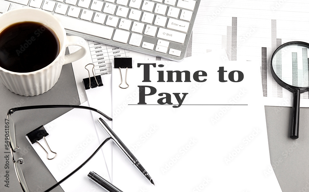 Poster time to pay text on a paper with magnifier, coffee and keyboard on grey background