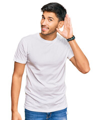 Young handsome man wearing casual white tshirt smiling with hand over ear listening an hearing to...