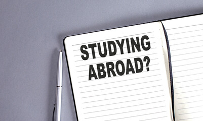 STUDYING ABROAD word on the notebook with pen