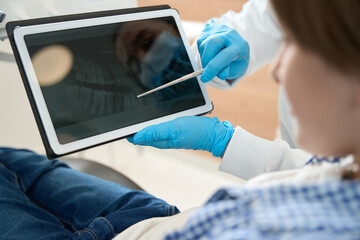 Dentist showing dental image on clipboard to young patient
