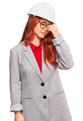 Young redhead woman wearing architect hardhat tired rubbing nose and eyes feeling fatigue and headache. stress and frustration concept.