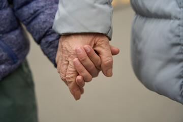 Child and grandmother hold hands while walking
