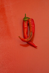 Fiery red italian frying peppers, mild, flavorful, on an orange background
