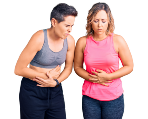 Couple of women wearing sportswear with hand on stomach because indigestion, painful illness feeling unwell. ache concept.
