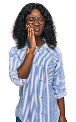 Beautiful african young woman wearing casual clothes and glasses touching mouth with hand with painful expression because of toothache or dental illness on teeth. dentist