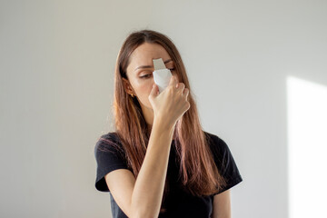 Young woman cleanses her facial pores with an ultrasonic scrubber. Self-care at home.