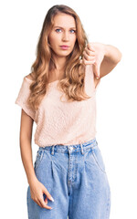 Obraz premium Young beautiful caucasian woman with blond hair wearing casual clothes looking unhappy and angry showing rejection and negative with thumbs down gesture. bad expression.