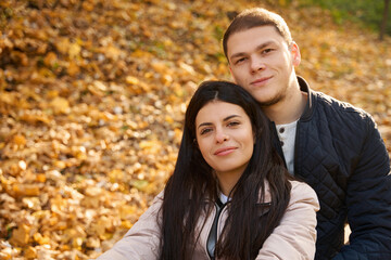 Pleasant couple is resting among the fallen yellow leaves