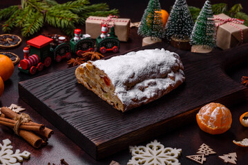 Fototapeta na wymiar Christmas pie stollen with marzipan, berries and nuts on a dark concrete background