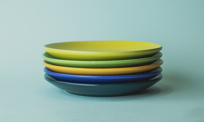 colored plates in a stack. saucers of different colors stand in a row