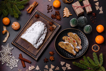 Fototapeta premium Christmas pie stollen with marzipan, berries and nuts on a dark concrete background