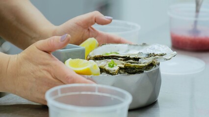 Oysters on ice in a metal bowl. Cooking oysters in the restaurant kitchen. Close-up of oysters in the kitchen. The cook serves a dish with oysters