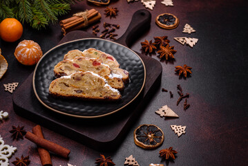 Christmas pie stollen with marzipan, berries and nuts on a dark concrete background