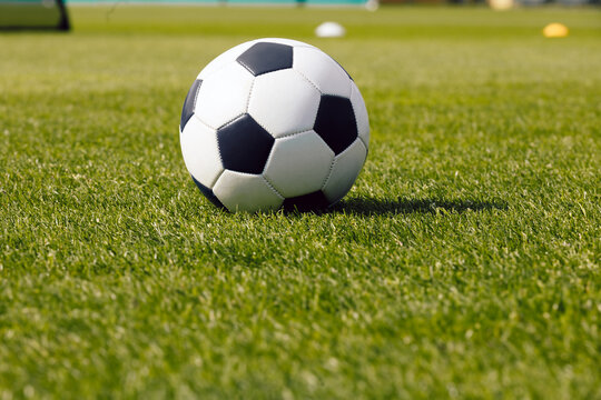 Classic football soccer ball on grass field. Side view on retro classic football ball. Image of sports soccer background