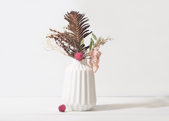 autumn and winter seasonal ikebana composition in white vase. dry flowers and leaves as home decor. cozy house decoration design details.