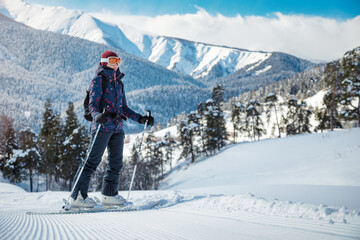 Amateur female skier enjoying the view of the mountains on the velvet slope on a sunny day at a ski...