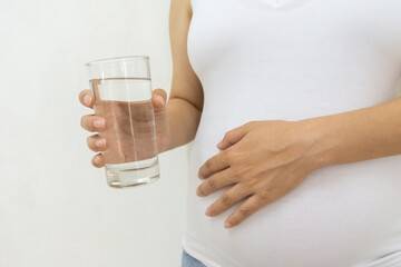 Close up photo of pregnant woman holding glass of water