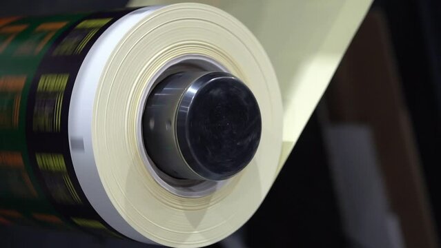 Roll of paper is unwound on the shaft of a printing machine in printing production at high speed close up
