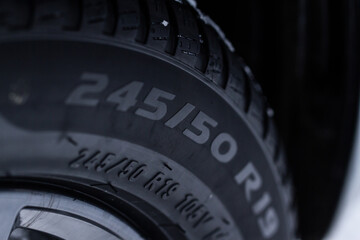 Close up view of snowy tire with tire width, height and wheel diameter designation. Winter tire...