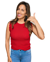 Young hispanic woman wearing casual clothes smiling doing phone gesture with hand and fingers like talking on the telephone. communicating concepts.