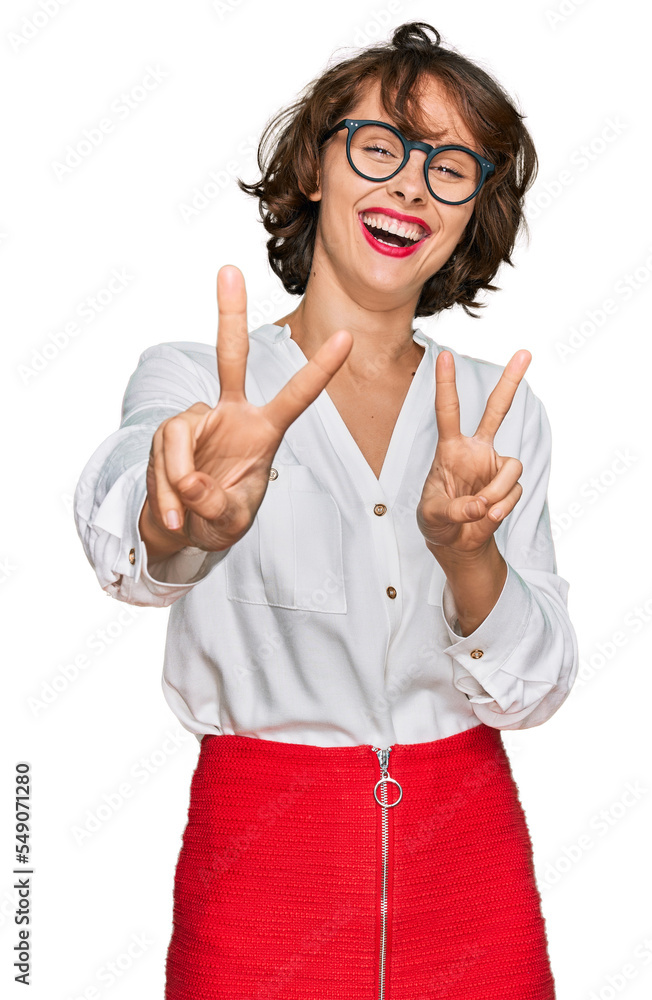 Sticker young hispanic woman wearing business style and glasses smiling looking to the camera showing finger