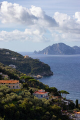 Fototapeta na wymiar Residential Homes on Mountain by the Sea with Capri Island in background. Near Touristic Town of Sorrento, Italy.