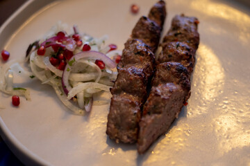 Grilled kebab with spices and grilled vegetables, sauces and fresh onions with pomegranate