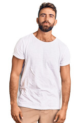 Young hispanic man wearing casual white tshirt relaxed with serious expression on face. simple and natural looking at the camera.