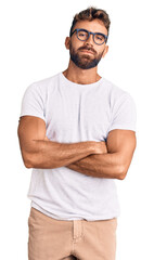 Young hispanic man wearing casual clothes and glasses looking to the side with arms crossed convinced and confident