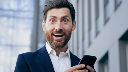 Close-up excited surprised man reading email notification on mobile phone getting good news happy satisfied emotional businessman winner wins online bet gambling get profitable business offer says wow