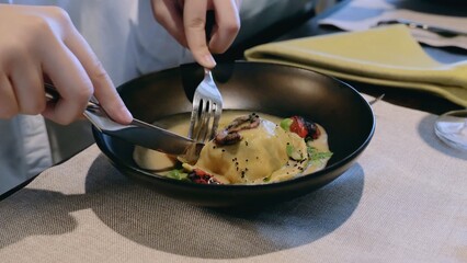 Close-up hands. Fish dish in dough. Signature dish in the restaurant. Dish and hands with cutlery close-up