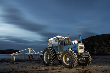 Seaweed collector tractor resting on the Asturias beach in the middle of the night