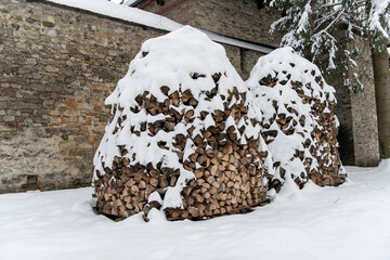 Moldovita, Romania, 2021-12-29. Pile of wood for the fire behind the Moldovita Monastery under the snow in the Bukovina region.