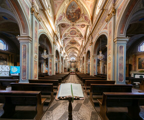 Fototapeta premium Boves, Italy - November 22, 2022: interior with frescoed vaults of parish church of san Bartolomeo with missal liturgical book in foreground