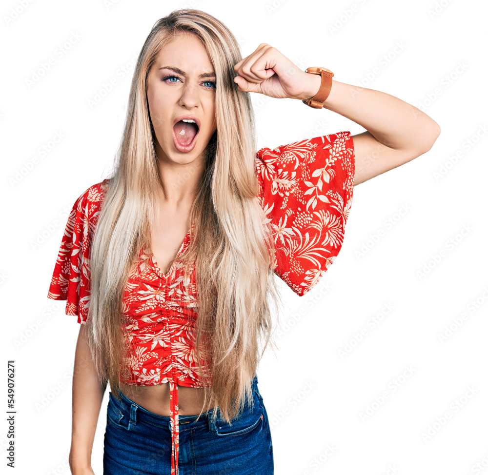 Wall mural beautiful young blonde woman wearing summer shirt angry and mad raising fist frustrated and furious 