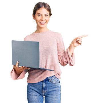 Beautiful Caucasian Woman With Blonde Hair Working Using Computer Laptop Smiling Happy Pointing With Hand And Finger To The Side