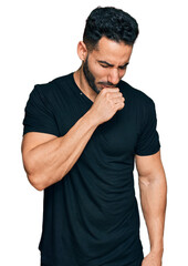 Hispanic man with beard wearing casual black t shirt feeling unwell and coughing as symptom for...