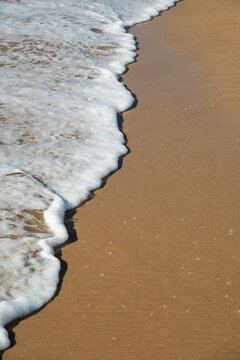 small wave with white foam arriving on the sand