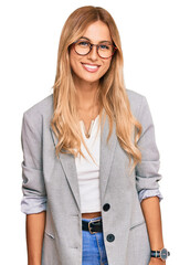 Beautiful blonde young woman wearing business clothes with a happy and cool smile on face. lucky...