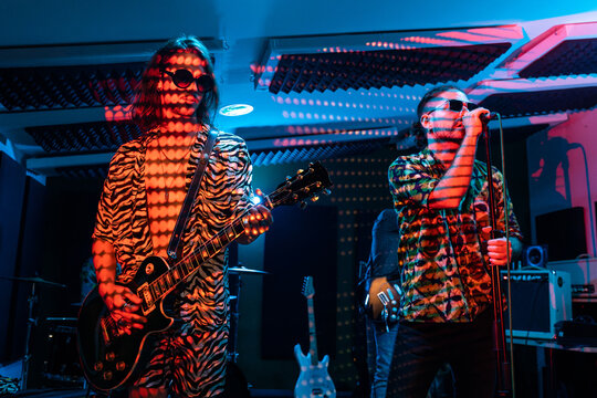 Band performing music while standing against projector with pixels lights