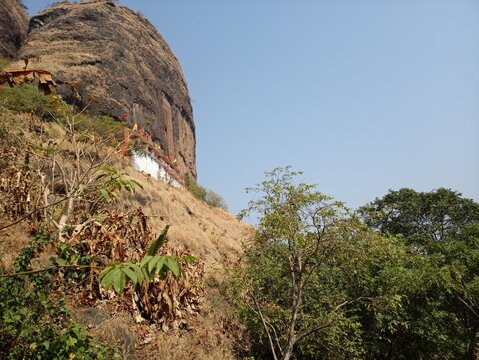 Trees on the large, straight and rocky mountain / Indian Mandir on the mountain