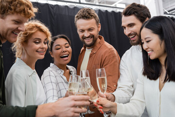 Multicultural business people clinking blurred champagne in office