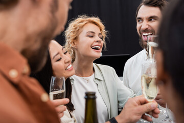 Excited interracial business people toasting with champagne in office