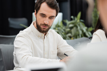 Fototapeta premium serious bearded businessman working in office on blurred foreground