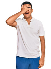 Fototapeta premium Young arab man wearing casual clothes smiling and laughing with hand on face covering eyes for surprise. blind concept.