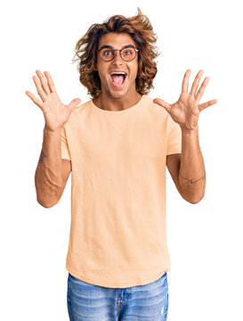 Young hispanic man wearing casual clothes and glasses celebrating crazy and amazed for success with arms raised and open eyes screaming excited. winner concept