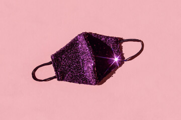 Protective face mask with glitter sequins. Corona virus pandemic concept background combined with parties and holidays.