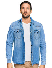 Young handsome man wearing casual denim jacket relaxed with serious expression on face. simple and natural looking at the camera.
