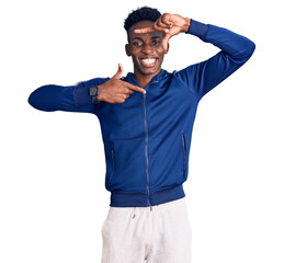 Young african american man wearing sportswear smiling making frame with hands and fingers with happy face. creativity and photography concept.